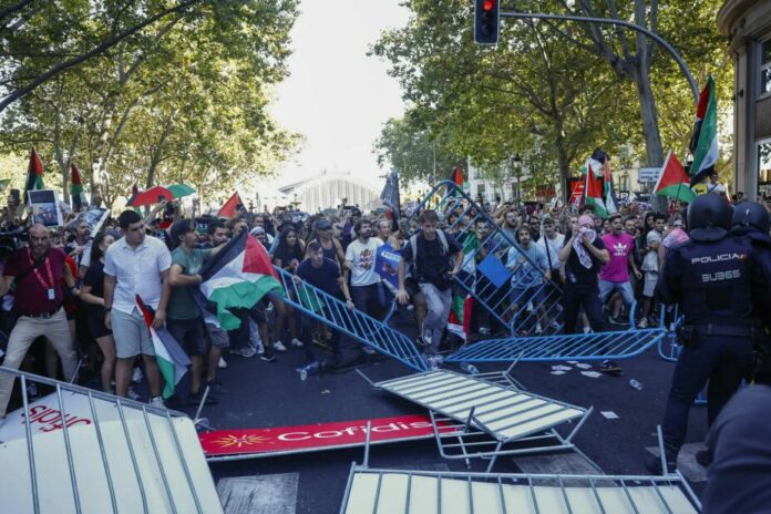 Los manifestantes propalestinos obstruyen el recorrido de los ciclistas en el Paseo del Prado. EFE.Rodrigo Jiménez